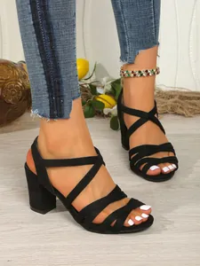 Detailed view of black suede chunky heel sandals featuring elegant criss-cross straps