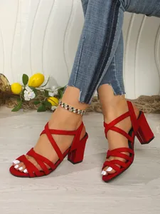 Red strappy block heel sandals with criss-cross design and open toe shown on feet
