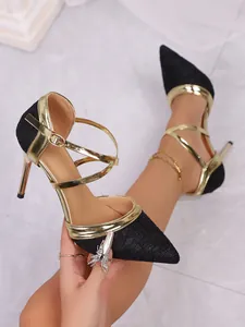 Detailed view of elegant black and gold pointed-toe stiletto sandals with ankle straps