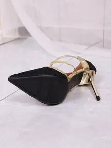 Close-up view of black lace pointed toe stiletto pumps with golden heel and anti-slip sole.