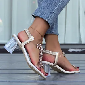 Close-up detail of rhinestone butterfly sandals with clear block heels and elegant square toe.