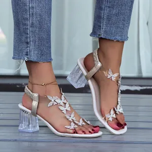 Elegant white rhinestone butterfly sandals with transparent crystal chunky heel on model feet
