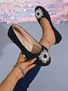 Detail von eleganten schwarzen Ballerinas mit funkelnder runder Strass-Schnalle für Damen.