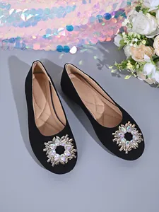 Nahaufnahme schwarzer Wildleder-Ballerinas mit funkelnder runder Strass-Schnalle