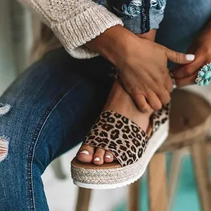 Detalle de sandalias de cuña con estampado de leopardo y suela de esparto trenzada.