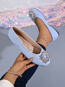 Detailansicht hellblauer Ballerinas mit funkelnder Strassschnalle und strukturierter Oberfläche.