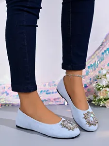 Detailansicht hellblauer Ballerinas mit funkelnder Strassschnalle an der Spitze.