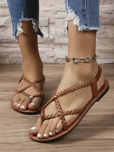 Primer plano de sandalias planas trenzadas de dedo para mujer en un color marrón