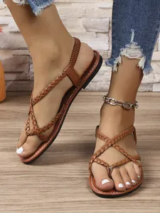 Primer plano de elegantes sandalias planas trenzadas marrones para mujer, ideales para playa.