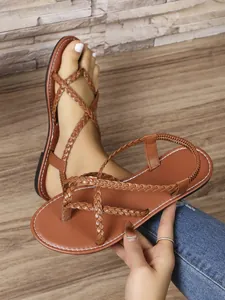 Vista detallada de las correas trenzadas marrones de estas sandalias planas para mujer