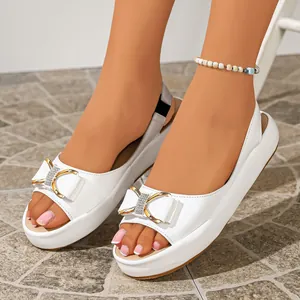 Detail of white platform sandals featuring a delicate rhinestone bow and gold accents.