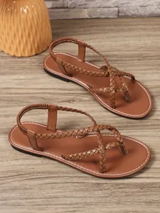 Elegantes sandalias de dedo trenzadas marrones con tira trasera elástica sobre madera