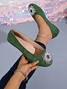 Nahaufnahme von grünen Ballerinas mit funkelndem Strass-Rundschnallendetail.