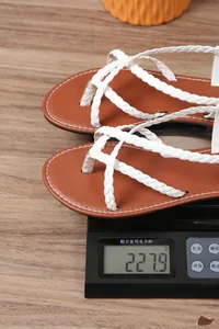 Detalle de las tiras trenzadas blancas de sandalias que pesan 227,9g en una báscula