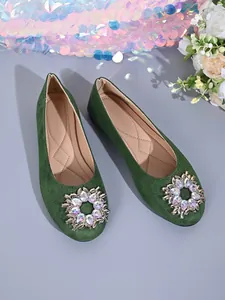 Detailaufnahme von grünen Wildlederflachschuhen mit funkelnder Strass-Rundschnalle.