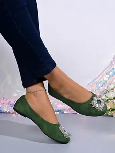Detaillierte Nahaufnahme eleganter grüner flacher Schuhe mit funkelnder Strass-Schnalle