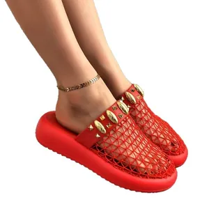 Mules rouges stylées en maille ajourée avec semelles compensées et clous dorés.
