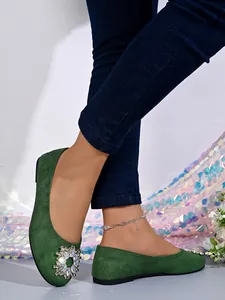 Nahaufnahme von grünen Wildlederballerinas mit dekorativer runder Strassschnalle.
