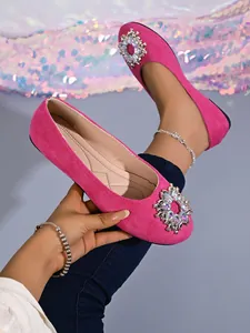 Nahaufnahme von fuchsiafarbenen Wildleder-Ballerinas mit eleganter Kristallschnalle.