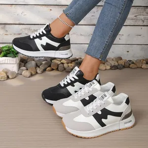 Vue latérale de baskets compensées tendance en noir et beige avec détails sur la languette