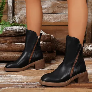 Detailed macro view of black vintage Chelsea boots with thick brown heels and side zippers.