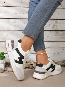 Détail de baskets élégantes blanches et noires portées avec un jean denim