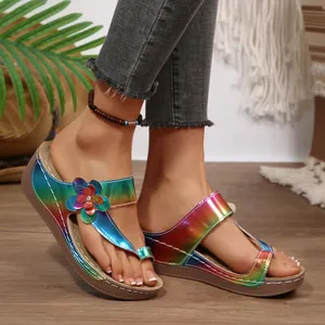 Close-up of colorful rainbow wedge sandals with floral accents being worn in a beach scene