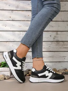 Vue détaillée de baskets compensées noires et blanches pour femmes portées avec un jean