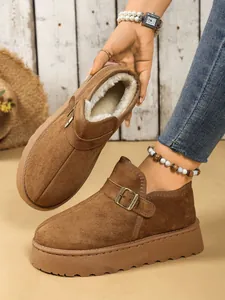 Detalle de botas de nieve marrones con plataforma, forro de pelo sintético y hebilla metal