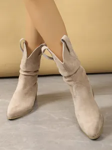 Vintage style beige suede ankle boots with pointed toe and chunky heel on model