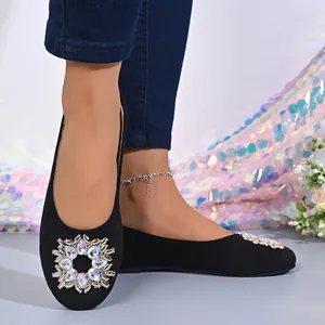 Gros plan détaillé de l'ornement floral en strass brillant sur des ballerines noires élégantes.