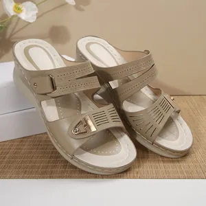 Detail view of beige wedge sandals with decorative gold metal buckles and cutout straps