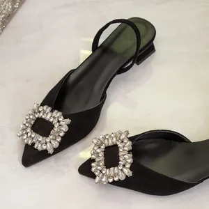Detail view of elegant black suede pointed-toe slingbacks with crystal square buckle.