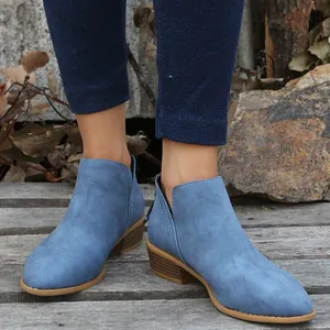Close-up van blauwe suède enkellaarsjes met puntige neus gedragen met jeans in buitenlucht.
