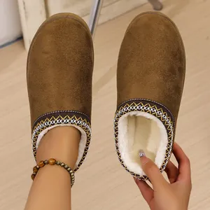 Detail of brown suede slippers with plush white faux fur lining and embroidery detail.