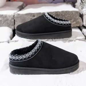 Close-up of black backless platform snow boots with woven trim in snowy setting.