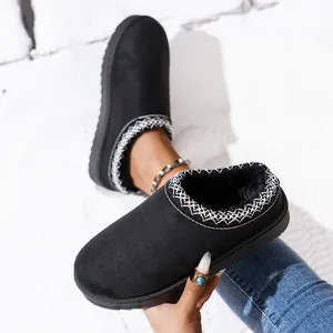 Close-up of black platform fuzzy slippers with white embroidered trim and warm lining