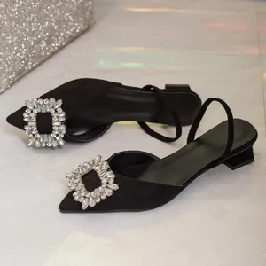 Detail view of black pointed-toe slingback sandals with rhinestone buckle