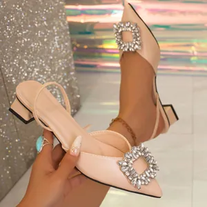 Macro view of the sparkling crystal buckle detail on a beige pointed-toe slingback.