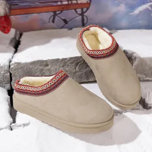 Cozy winter mule slippers with faux fur lining and ethnic embroidered trim set on snow.