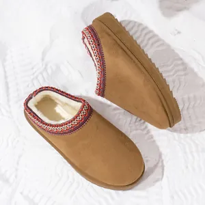 Detail of brown suede mules with white fleece lining and embroidered trim.