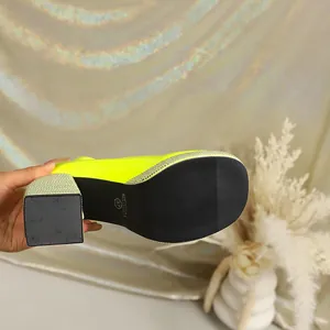 Close-up bottom view of neon yellow chunky heel Mary Jane shoes with rhinestone platform