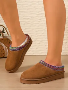 Close-up of brown suede snow boot slippers with colorful embroidery and faux fur lining
