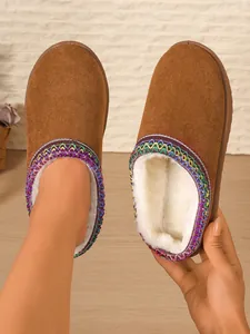 Close-up of brown suede slippers with white fur lining and colorful embroidery
