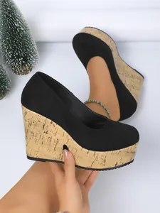 Detalle de zapatos de cuña en ante negro con suela de plataforma de corcho.