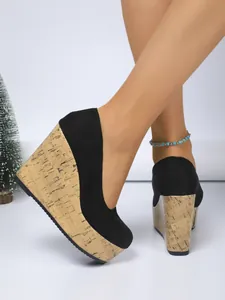 Primer plano de zapatos de cuña de ante negro con plataforma de textura de corcho.