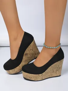 Primer plano de zapatos de cuña en ante negro para mujer con plataforma de corcho