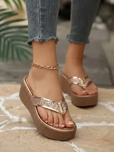 Detail view of stylish rose gold glitter platform wedge flip-flops with a gold anklet accessory