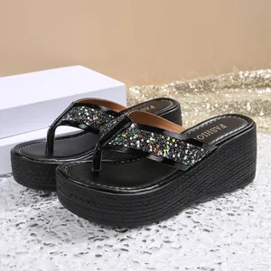 Close-up of black platform flip-flops with glittery straps and woven wedge heel