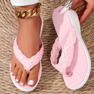 Close-up view of pink women's wedge flip-flops featuring braided straps on a straw mat background